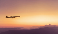 plane flying at sunset over mountains
